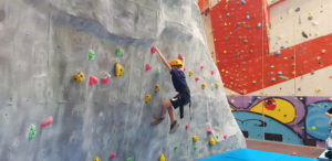 Young person learning to climb on a climbing wall
